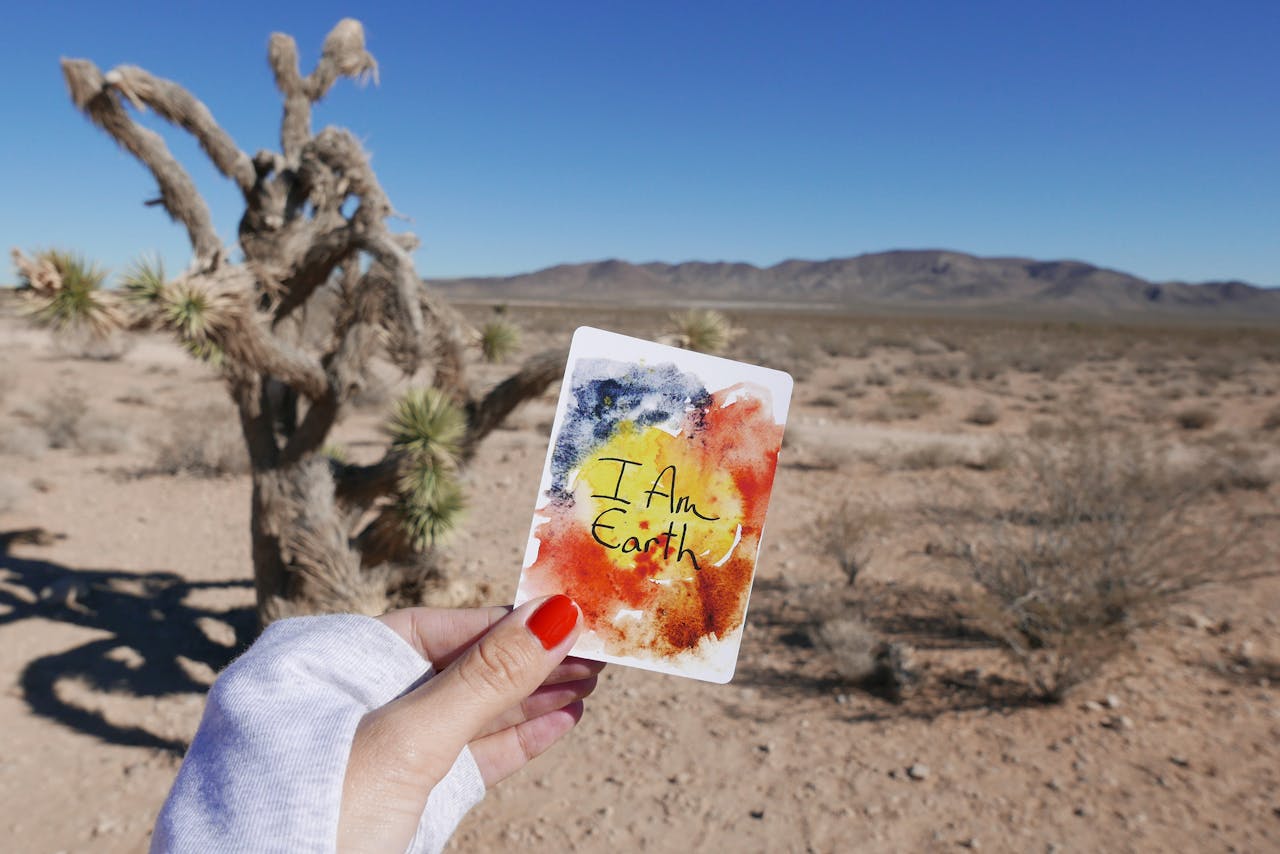 Vibrant card held against Nevada desert landscape, showcasing nature and creativity.